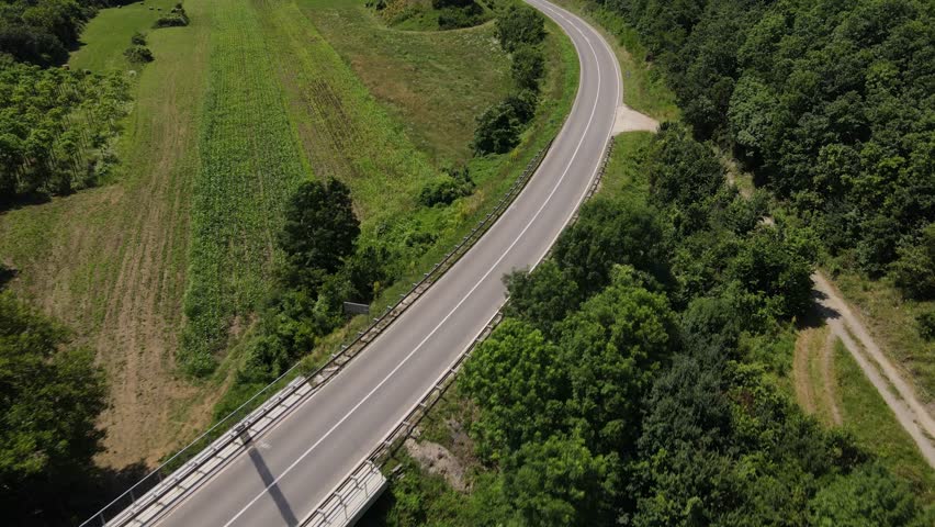 scenic beauty of an asphalt road on a sunny day as cars pass by from a drone's perspective car drive on the asphalt aerial drone point of view in serbia