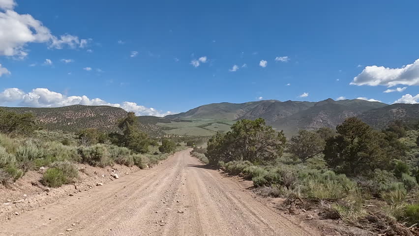 Driving dusty dirt mountain road Utah POV 1. Off road trail riding in 4x4 all terrain vehicle for sport and recreation. Fun and adventure riding in central Utah. Mountains and desert landscape.