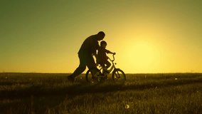 Childhood dream to ride bike. Dad teaches her little daughter to ride bicycle, sunset. Young father teaches child to keep balance while sitting on bicycle. Holiday family. Dad baby, Parental support. - Powered by Shutterstock - Get 15% off with code: PIKWIZARD15