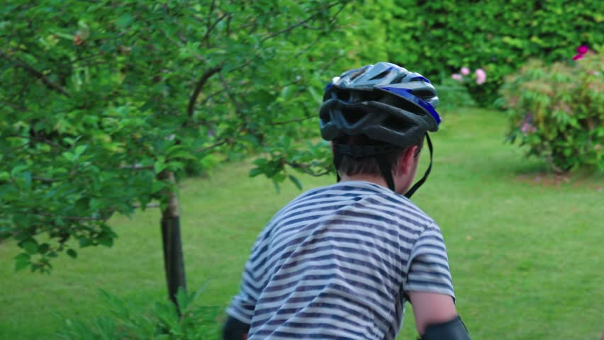 View of young boy learning inline skating in garden on sunny summer day. Sweden.