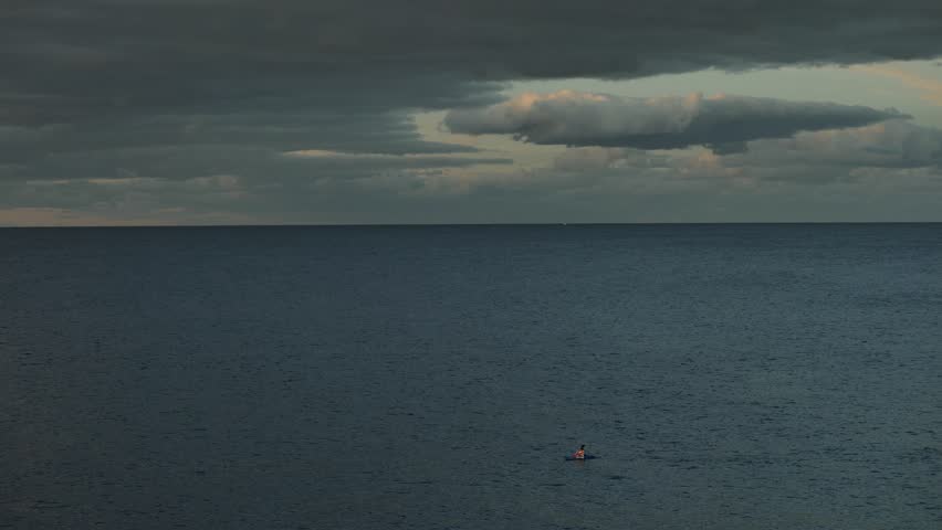 SYDNEY, AUSTRALIA. JULY 22 2022. Birds fly past a lone canoeist out at sea, slow motion.