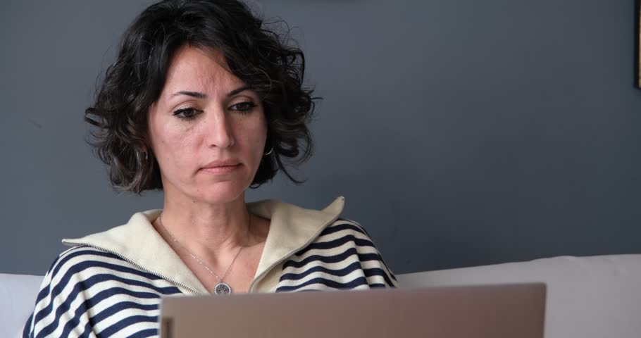 Stressed woman looking at laptop. Home office concept: Beautiful mixed race young entrepreneur woman, brown short curly hair, striped casual sweatshirt, looking at PC screen. Female person working. Royalty-Free Stock Footage #1105713949