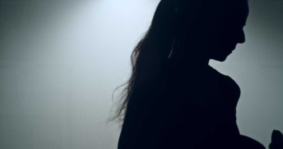 Slow motion of a woman boxer walking toward the camera in silhouette. Tough sport woman walking with boxing gloves