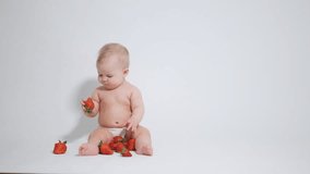 6 month old baby plays with a red berry. video filmed on a light background