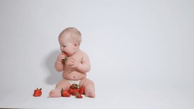 6 month old baby plays with a red berry. video filmed on a light background