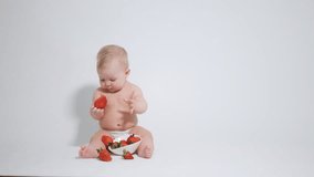 A 6 month old baby shows interest in red strawberries by looking at them. Video filmed in the studio