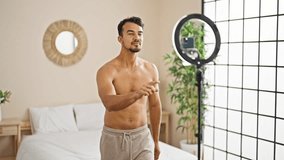 Young hispanic man recording fitness video training at bedroom