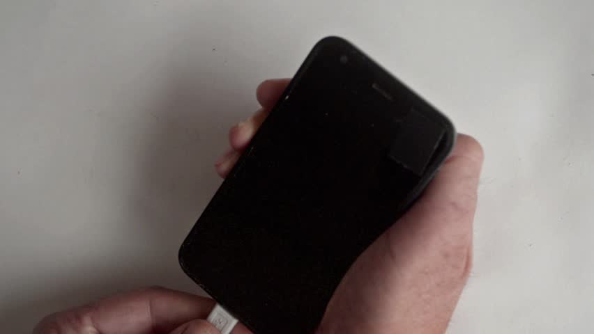 the man holds the charger cable ,another hand holds smartphone ,the smartphone indicator shows the battery charging.  - Powered by Shutterstock - Get 15% off with code: PIKWIZARD15