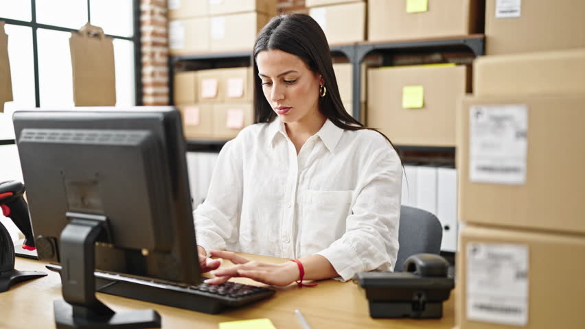 Young beautiful hispanic woman ecommerce business worker using computer talking on telephone at office
