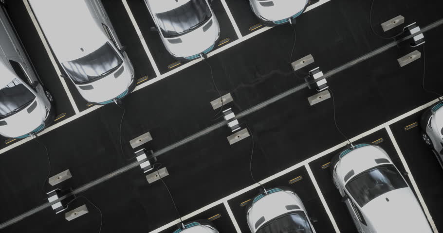 OVERHEAD HIGH ANGLE Fleet of generic electric EV EDV delivery vans charging on charging stations inside company parking garage Royalty-Free Stock Footage #1105730291