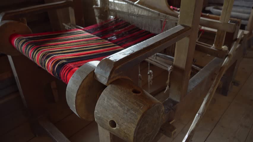 Ancient loom inside an old hut, a knitting and spinning machine. An old manufactory for the production of belts, towels and clothes