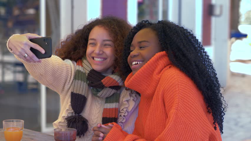 two girlfriends fool around and do selfie for a social network. African American and Hispanic