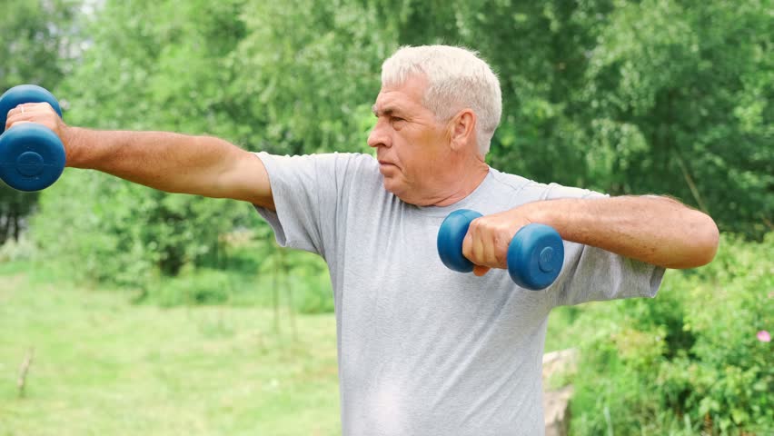Senior man working out outdoors. Person lifting dumbbells. Old male exercising at park. Healthy people lifestyle. Active sport training. Older elderly sportsman doing fitness exercise. Workout session
