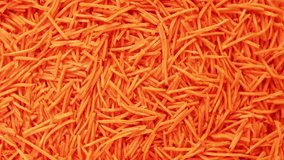 Grated Carrots Background is Spinning. Fresh Juicy Chopped Carrots. Food Orange Color Backdrop. Shredded Carrot Abundance is Rotating. Crushed, Cut Vegetables for Soup, Garnish, Salad. Healthy Eating.