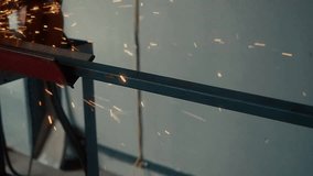 Worker cuts metal channel with circular saw in production room and sparks fly. Video of authentic workflow.