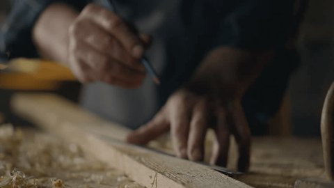 Стоковое видео: Carpentry, Worker Definitely Marks marks with a pencil draws a line In a carpentry shop Camera in motion Furniture assembly worker Is at the workplace at a table In a furniture shop, tools

