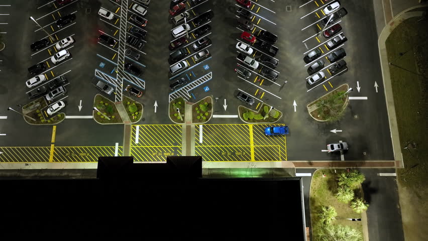 Aerial night view of many cars parked on parking lot with lines and markings for parking places and directions. Place for vehicles in front of a grocery mall store Royalty-Free Stock Footage #1105744805