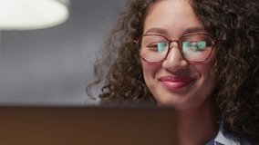 Happy Hispanic young business woman looking at computer screen, waving hello. Pleasant attractive curly female professional holding video call with friends.