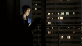 Elegant woman using gadget standing by window at home at night. Businesswoman using a tablet to work while standing by the window of an office late at night. - Powered by Shutterstock - Get 15% off with code: PIKWIZARD15
