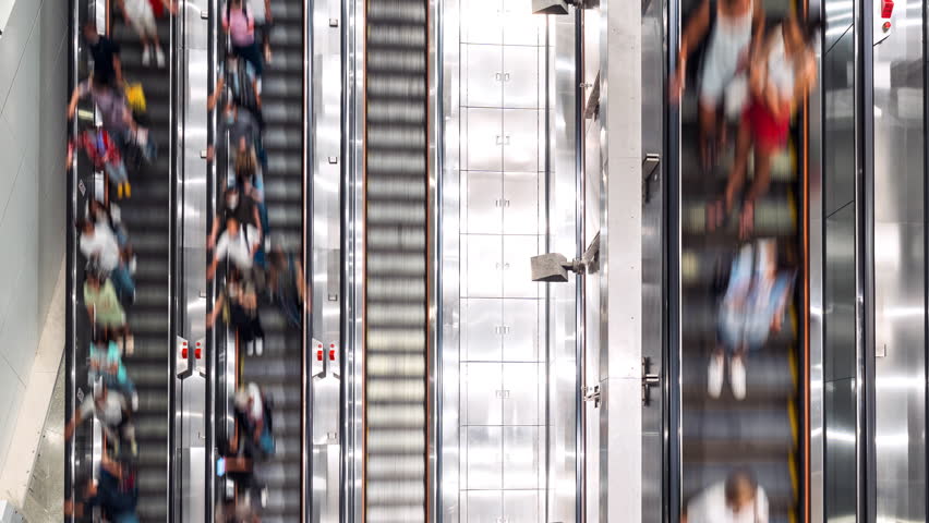 Time-lapse of Asian people transport on escalator at subway underground station in Hong Kong. Public transportation, Asia city life, or commuter urban lifestyle concept. Top high angle view, tilt down