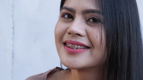 Close-up of beautiful young female face look at camera and confident. Girl wide smiling with healthy white teeth. Portrait of Asian woman lady. footage 