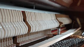 close up on the interior of a piano, hammers and strings mechaninsm of a vertical piano being played