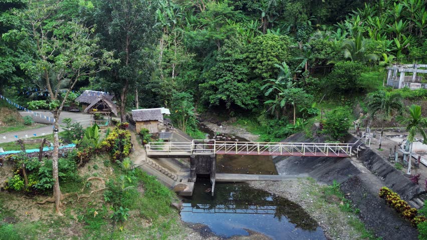 Idyllic aerial dolly of tropical jungle and river park, and metal bridge in Catanduanes, Philippines.