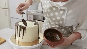 cook a cake in the kitchen, decorate with chocolate streaks. Young female pastry chef cooking a beautiful high sponge cake, pastry chef works at home, bright kitchen, video of the process