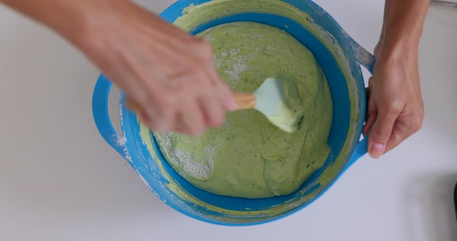 Woman mixing spinach with dough for healthy bakery, top view