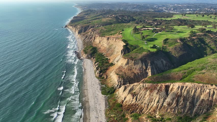 Aerial view panning up looking at Torrey Pines Golf Course and Blacks Beach in San Diego near Del Mar and La Jolla with a great view of the cliffs ocean and gliderport. Royalty-Free Stock Footage #1105762707