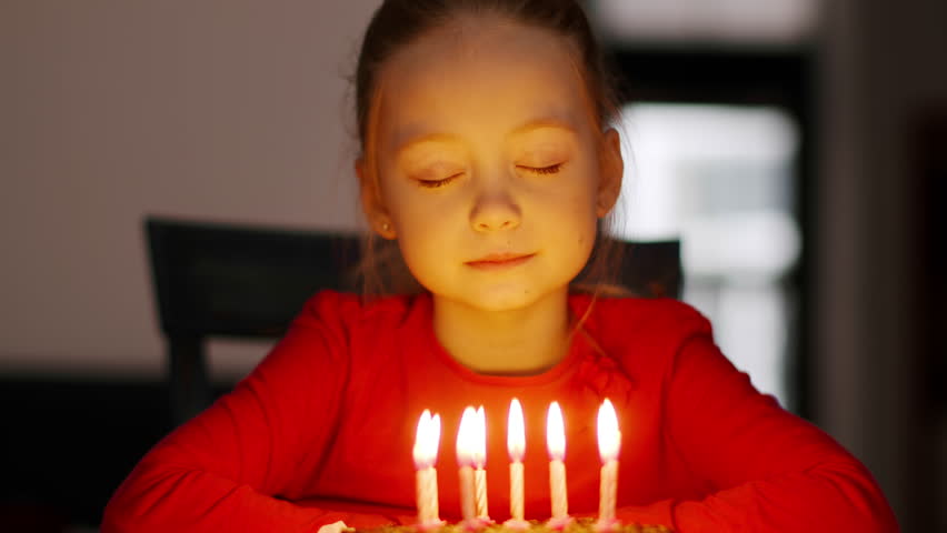 Cherished wish. Close up portrait of adorable carefree little birthday girl making wish and blowing candles on holiday cake, celebrating at home interior Royalty-Free Stock Footage #1105764019