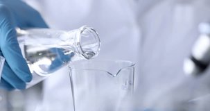 Scientist chemist pouring water from flask into glass 4k movie