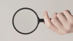 Vertical video. Magnifying glass. Zooming tool. Woman hand exploring empty space with loupe examining isolated on gray background.