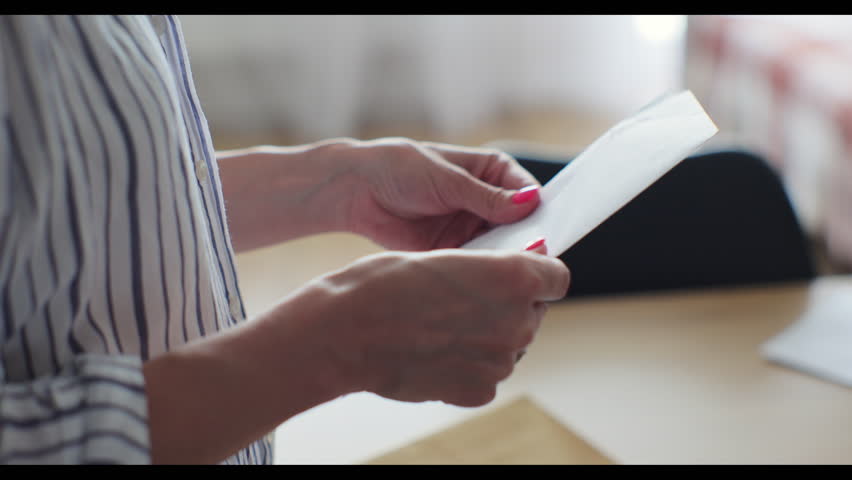 Close-up woman hands pull out paper envelope utility bill paper letter bank documents. Woman hands opening paper letter post invoice tax forms.