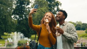 Young couple travelling through city park eating ice cream together posing for picture for social media- shot in slow motion - Powered by Shutterstock - Get 15% off with code: PIKWIZARD15