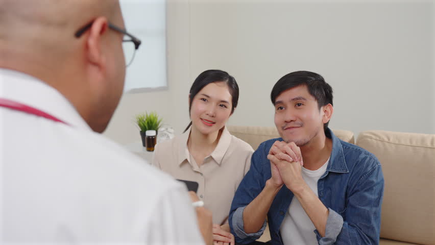 Asian couple discussing infertility problems with a handsome doctor, They feeling happy and holding hand together when received good news from the doctor. 4k resolution. Royalty-Free Stock Footage #1105773779