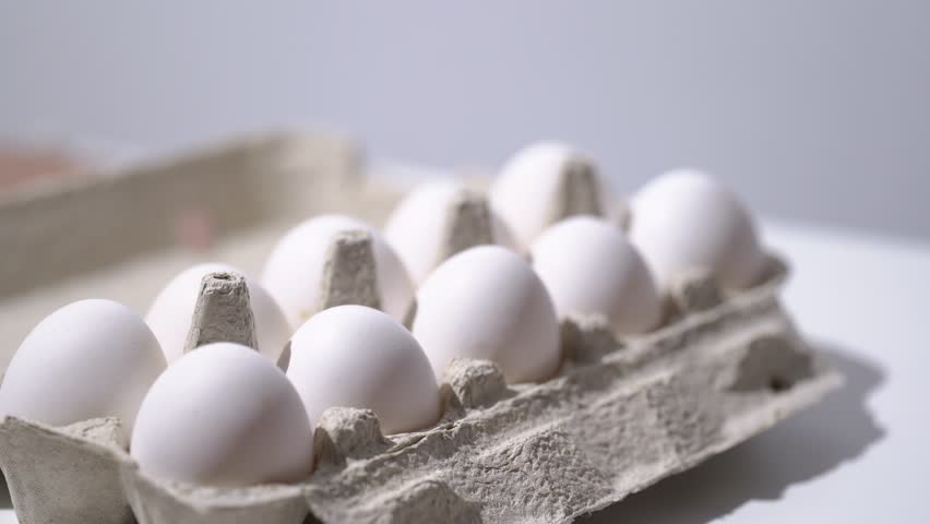 Chicken egg rotates on a white background. Close-up of an egg. Fresh Protein Food. Chicken Eggs In Eggshell Cardboard Box. Chicken Coop Package. Raw Food Breakfast Hen Product.  Royalty-Free Stock Footage #1105774939