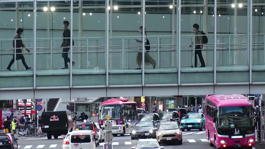 SHIBUYA, TOKYO, JAPAN : Aerial view of crowd of people walking at the pedestrian deck. Street and road traffic under the deck. Japanese city life and transportation concept video. Time lapse shot. Royalty-Free Stock Footage #1105775223