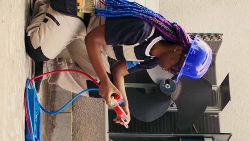 Vertical video Capable electrician preparing for yearly condenser maintenance. Meticulous wireman unpacking toolset box with professional gear needed to repair faulty air conditioner internal