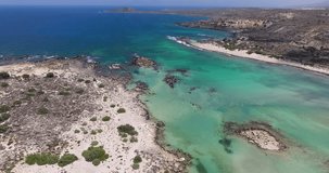 drone aerial video view of Elafonissi Beach with pink send blue turquoise sea mountains and rocky shore in crete greece 4k high quality footage