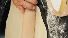 Rolling out dough for pizza with rolling pin, close up of hands. Vertical video. Woman chef baker cooking homemade italian pizza Margherita. Online culinary lessons. Cooking concept