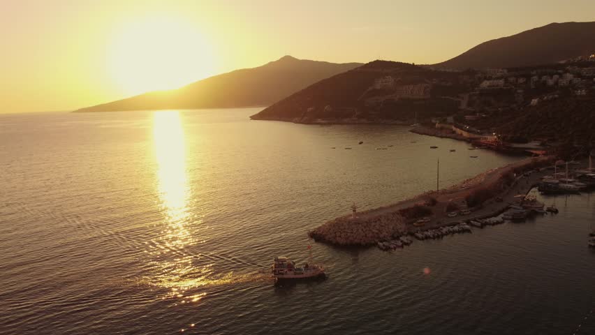 Aerial view of Bali beach island with boat port, and sliver of sand on Sunset beach in the evening, sunset sea view with mountains, drone aerial.