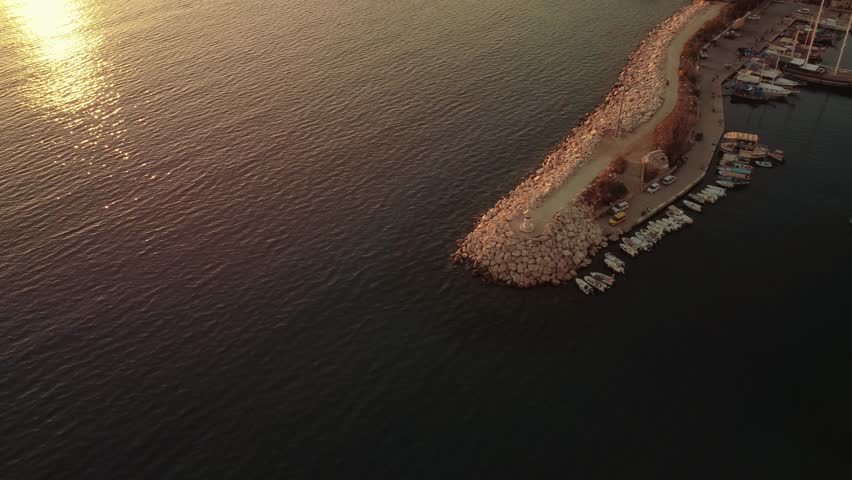 Aerial view of Bali beach island with boat port, and sliver of sand on Sunset beach in the evening, sunset sea view with mountains, drone aerial.