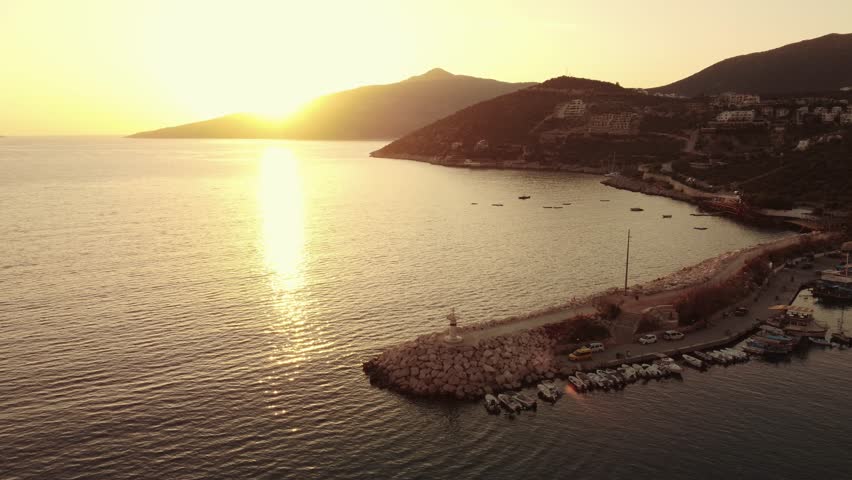 Aerial view of Bali beach island with boat port, and sliver of sand on Sunset beach in the evening, sunset sea view with mountains, drone aerial.