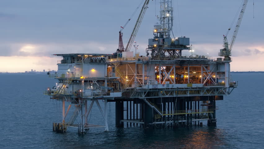 Offshore oil drilling rig and lots of ships on the horizon in the Pacific Ocean. Environmental impact of offshore oil rigs on marine ad human life in USA. High quality 4k footage