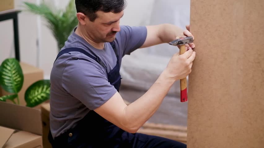 Carpentry business man creating custom furniture from quality wood materials for office and home interiors from factory specialist hammering nail into wooden wardrobe