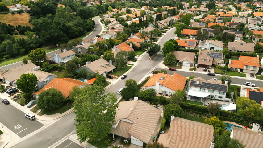 Flyover above beautiful of suburban. Drone footage of residential area. Aerial view of suburban neighborhood villas and road. Houses with pools, trees and orange roofs. Los Angeles, California, USA Royalty-Free Stock Footage #1105791871
