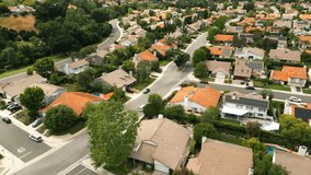 Flyover above beautiful of suburban. Drone footage of residential area. Aerial view of suburban neighborhood villas and road. Houses with pools, trees and orange roofs. Los Angeles, California, USA