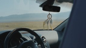 The car stopped on the road among the mountains and desert. The dreamcatcher inside the interior of the car is being stirred by the wind. Summer vacation trip. Road trip and wanderlust - Powered by Shutterstock - Get 15% off with code: PIKWIZARD15