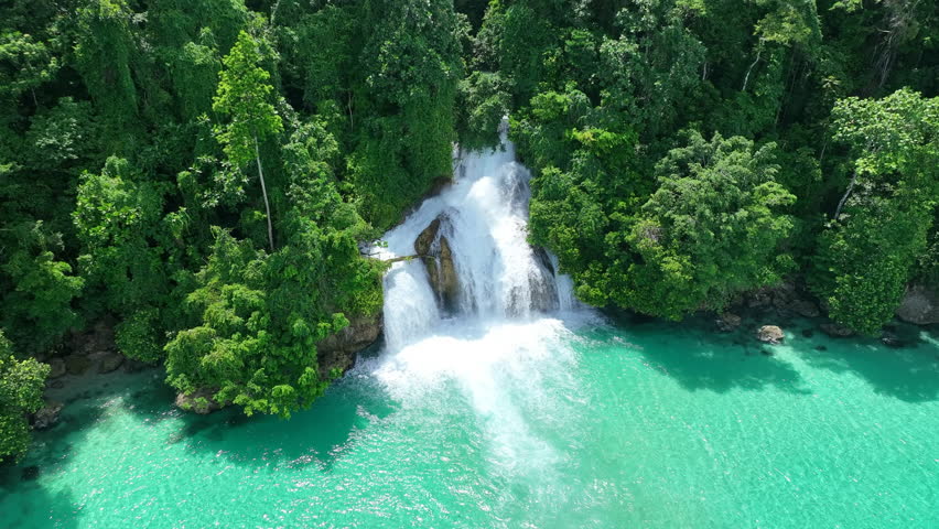 The scenic Momon waterfall tumbles from the primordial rainforest of West Papua into the shallow sea. This spectacular waterfall is found about a day